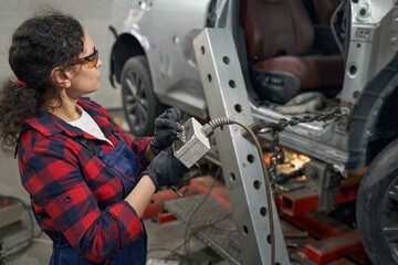 Female auto mechanic using car diagnostic equipment in garage