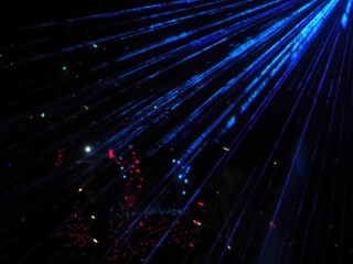 Bright neon blue beams illuminate a dark area with bright glowing lights. Laser show. Defocused image. Long exposure