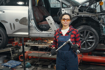 Female auto mechanic holding car repair tool in service station