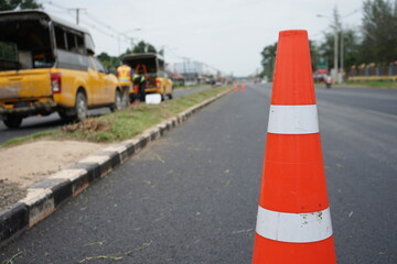 Red rubber cone and blurry background image of road maintenance agency work.