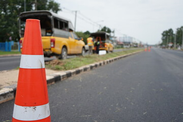 Red rubber cone and blurry background image of road maintenance agency work.