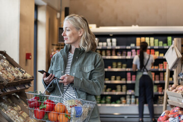 Mid adult female with smartphone in a grocery store 