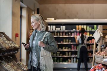 Mid adult female with smartphone in a grocery store 