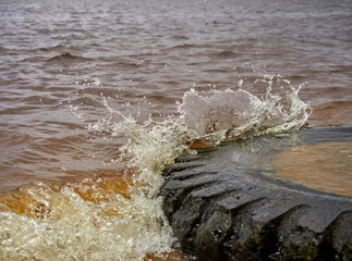 view of the sandy beach by the Baltic Sea. Seashore with old car tires and concrete, human waste,...