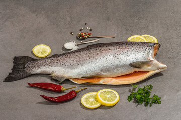 Raw trout carcass with spices and herbs on a grey stone concrete background. Sea fish, healthy food
