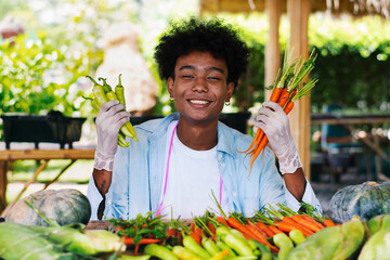 Teenager boy holding vegetables at tropical fruit and vegetables market shop