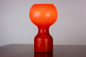 A 60s modern orange bedside lamp with glass spaceage vintage midcentury design front side view isolated on white background with warm orange light in the studio living room creative HQ 60s furniture 