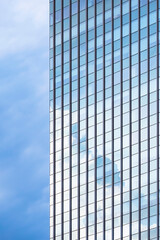 Sky reflection on surface of glass skyscraper against cloudy sky background in vertical frame 