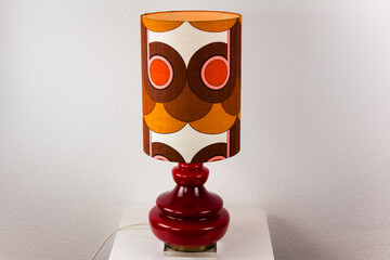  A 60s modern red bedside lamp with glass base and fabric lampshade vintage midcentury design front side view isolated on white background with warm orange light studio living room 60s furniture 