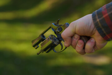 Unrecognizable man holding revolver with full cartridge in the drum Close-up.