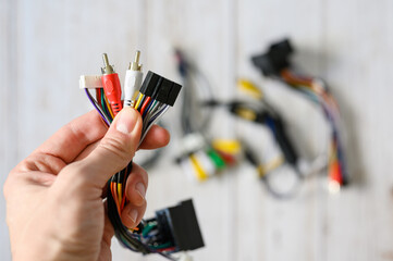 A bundle of wires with different connections in a hand against a background of a pile of various electronic wires. selective focus