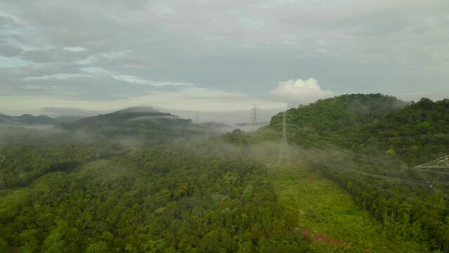Video 4K, Aerial view Morning scenic on high mountains with electricity pylon Pang Puay, Mae Moh, Lampang, Thailand. Beautiful morning with golden sunrise and fog flowing.