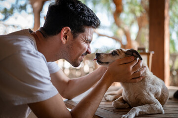 close up. a dog licks a young man,s nose in the garden