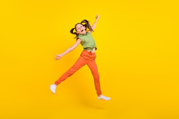 Fototapeta na wymiar Photo of carefree pretty student girl wear green shirt smiling jumping high arm sides isolated yellow color background