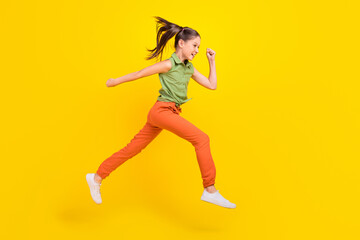 Fototapeta na wymiar Photo of funky pretty student girl wear green shirt smiling running fast jumping high isolated yellow color background