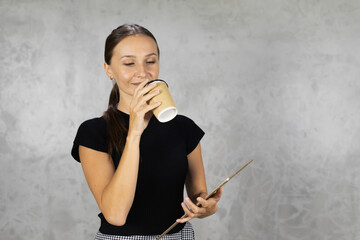 Fototapeta premium portrait of happy smiling pretty woman drinking coffee in cup and holding tablet with copy space at background. pretty caucasian woman relax working business at home office