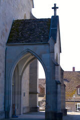 Fototapeta premium Entrance of medieval church named Pfarrkirche St. Johann with stone cross at the old town of City of Rapperswil-Jona on a sunny spring day. Photo taken April 28th, 2022, Rapperswil-Jona, Switzerland.