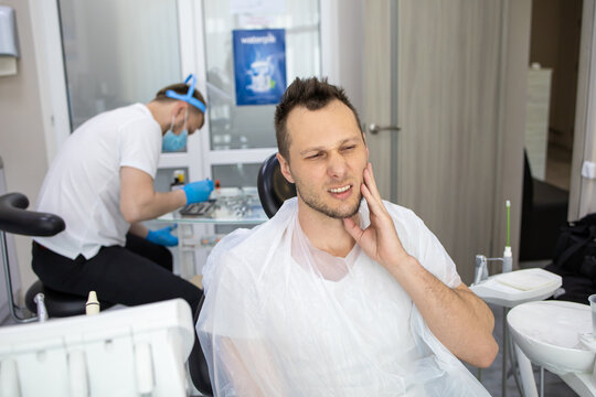 Practitioner male dentist drilling tooth to patient in dental studio