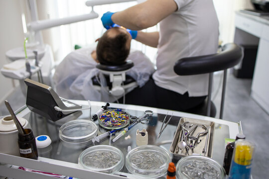 Practitioner male dentist drilling tooth to patient in dental studio