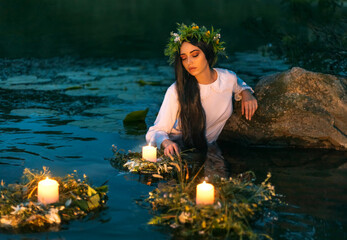 Slavic woman nymph stands in water herbal wreath floa candles burning. Fantasy girl mermaid. White...