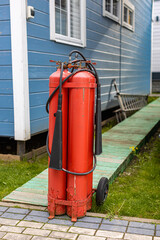 Fototapeta na wymiar large fire extinguisher on wheels in the courtyard of the house