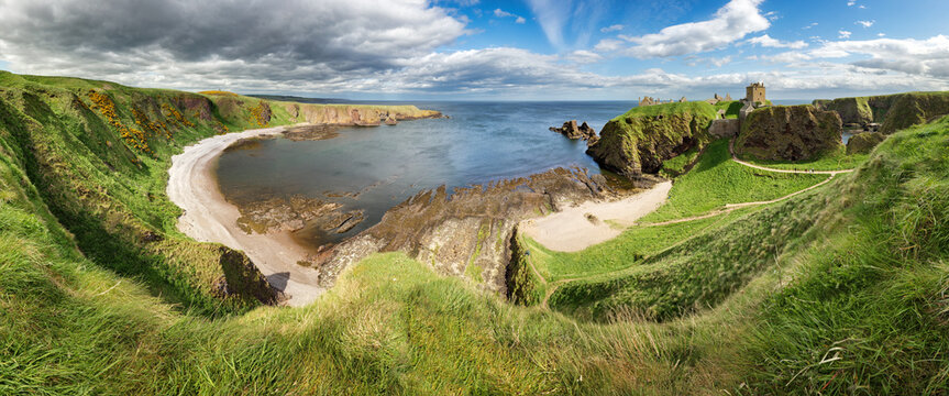 Panorama of a cliff with ancient castle in a bay with blue sky and white clouds in Dunnottar Castle, near Stonehaven, Aberdeenshire, Scotland - UK