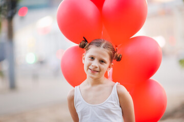 European girl child preteen with red balloons, close-up, sunny summer day. Kid with funny sun glasses and haircut With sticky freckles