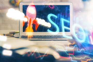 Double exposure of table with computer and seo drawing hologram. Search optimization concept.