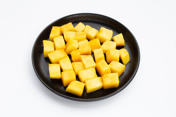 Yellow mango cube slices in black plate on white background.