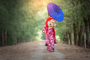 Thai girl wearing a kimono stands in the way of a tunnel searching for wood.