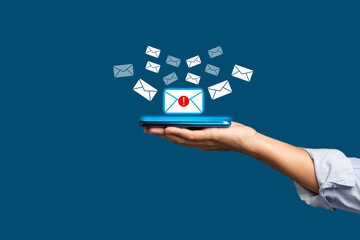 Email marketing concept. A smartphone on the palm with receives a new message with email icons on a virtual screen over a blue background
