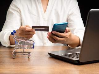 Close-up of hands holding a credit card and smartphone for online shopping while sitting in the office
