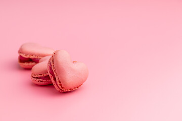 Heart shaped Sweet macarons on pink background.