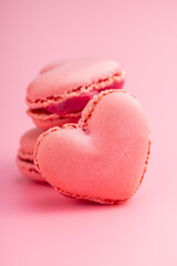 Heart shaped Sweet macarons on pink background.