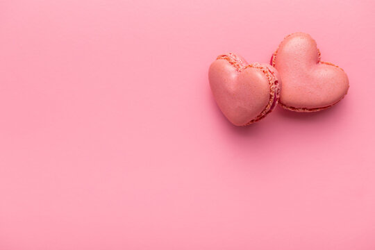 Heart shaped Sweet macarons on pink background.