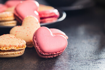 Heart shaped Sweet macarons on black table.