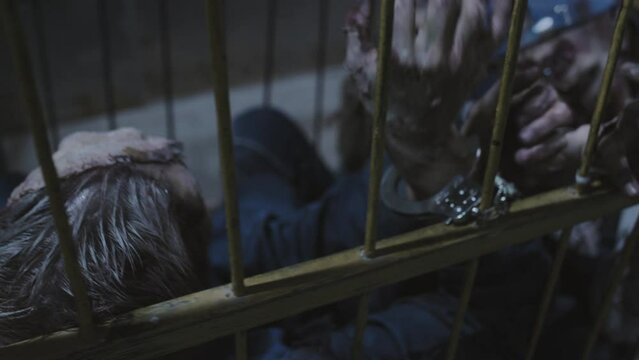 Soldier with shaved head transporting zombies in cage on wheels in dark basement of industrial building