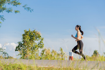 Asian woman jogging in the park, healthy lifestyle and sports concept. woman jogging in the park in sunlight on a beautiful summer day