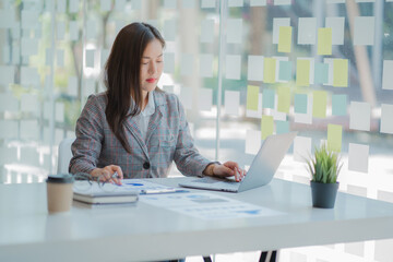 Asian businesswoman uses a calculator to calculate her company's financial results and budget....