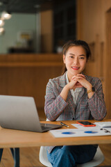 Asian businesswoman paying bills online with laptop in office Beautiful girl and checkbook phone willing to pay bills to start a business, financial calculator, accounting concept, vertical image.