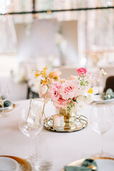 Festive banquet. Round tables which are beautifully decorated with plates, candles and a beautiful composition of flowers and table number in the center