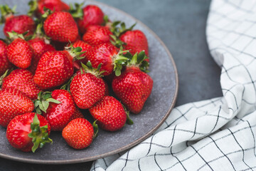 Delicious, fresh strawberries in a stylish plate on a concrete background. Top view with space to copy.