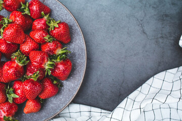 Delicious, fresh strawberries in a stylish plate on a concrete background. Top view with space to copy.