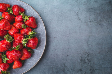 Delicious, fresh strawberries in a stylish plate on a concrete background. Top view with space to...