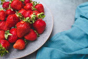 Delicious, fresh strawberries in a stylish plate on a concrete background. Top view with space to copy.