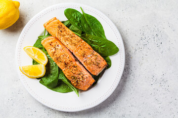 Fried with spices pieces of salmon with spinach on white plate. Diet recipe concept.