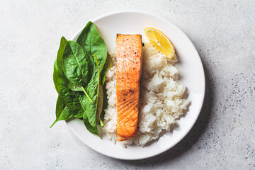 Fried salmon with rice and spinach on white plate. Diet recipe concept.