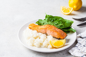 Fried salmon with rice and spinach on white plate. Diet recipe concept.