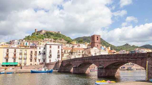 Timelapse of picturesque town buildings and boats next to Roman bridge and Temo River, Malaspina Castle in background, Bosa, Italy