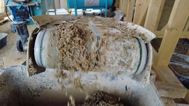 Tilt-down of fresh hempcrete falling from a conveyor belt into a box at slow-motion 60fps